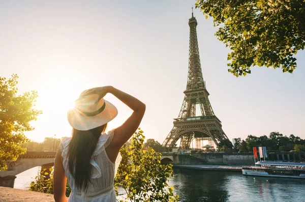 夕暮れ時にパリのエッフェル塔の前に立つ太陽の帽子と白いドレスの若い女性観光客 フランスの旅行 観光の概念 高品質の写真 ロイヤリティフリーのストック写真