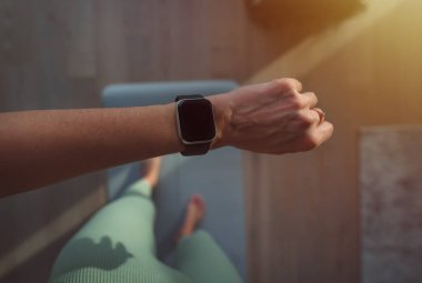 Woman checking fitness app on digital smart watch during workout. Closeup of hands checking an app in smartwatch. Home workout or crossfit or gymnastics concept. Mockup or copy space.