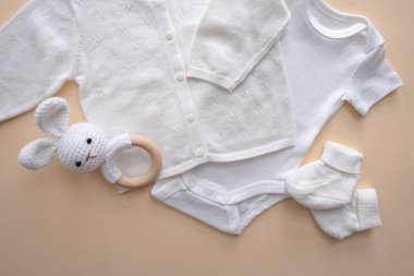 Beyaz bebek kıyafetleri, aksesuarlar ve kahverengi arka planda oyuncaklar. Yeni doğmuş vücut, şapka ve çoraplar. Yeni doğan temel ihtiyaçlar ve annelik kavramı. Yüksek kalite fotoğraf