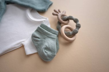 Bebek kıyafetleri, aksesuarlar ve kahverengi arka planda oyuncaklar. Yeni doğmuş vücut, kazak ve çoraplar. Yenidoğan gereksinimleri ve annelik konsepti. Yüksek kalite fotoğraf