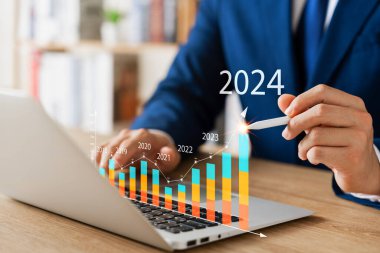 Businessman analyzes profitability of working companies with digital augmented reality graphics, positive indicators in 2024, businessman calculates financial data for long-term investments.