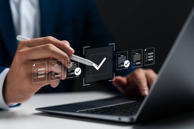 Dijital belge simgelerine sahip dizüstü bilgisayar kullanan işadamı, kontrol işareti ve çevrimiçi belge onayı, dijital form kontrol listesi, iş listesi yönetimi ve performans izleme.