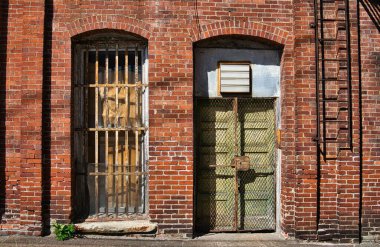 Terk edilmiş bir binada parmaklıkları olan eski bir kapı ve pencere.  