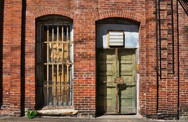 Terk edilmiş bir binada parmaklıkları olan eski bir kapı ve pencere.  