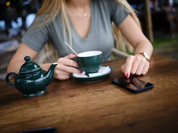 Uma Mulher Senta Cafetaria Desfrutando Chá Usa Seu Telefone Para — Fotografia de Stock