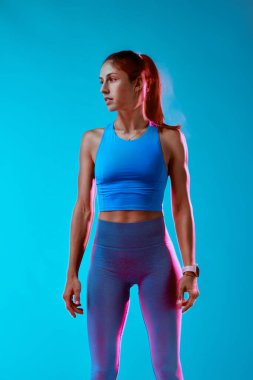 Ayakta duran ve başka tarafa bakan sporcu kadının portresi. Stüdyo çekimi. Uzun pozlama hareketi.