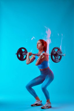 Halter kaldıran bir kadın vücutçunun stüdyo fotoğrafı. Uzun pozlama hareketi yakalaması.