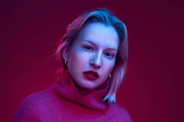 Portrait of a serious young blond woman isolated on magenta background. Viva magenta.