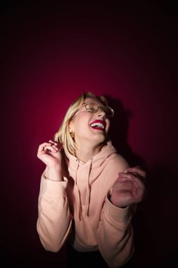 A young blond woman standing in front of the magenta background. Viva magenta.