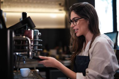 Kahve dükkanında durup kahve makinesinde espresso yapan Barista..