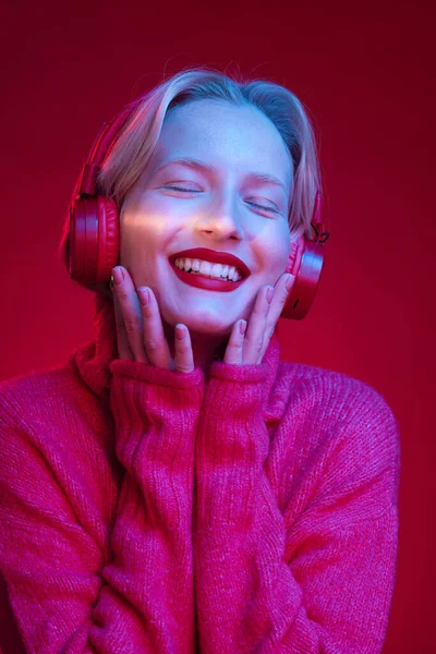 マゼンタの背景に隔離されたまま 無線Lanのヘッドフォンで音楽を聞いて笑顔の幸せな若い女性 Viva Magenta 今年の色 — ストック写真