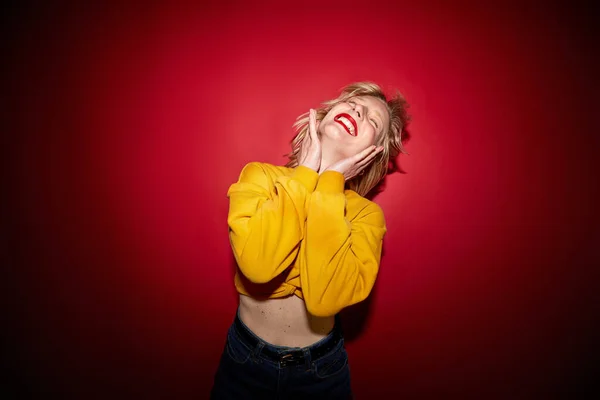 stock image A cheerful woman is dancing isolated on red background and laughing.