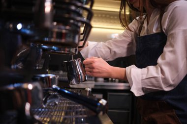 Kafeteryadaki kahve makinesinde süt ısıtan bir garsonu kapat..