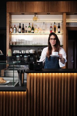 Dost canlısı bir barista, kahve dükkanında dururken müşteriye bir fincan taze kahve veriyor..