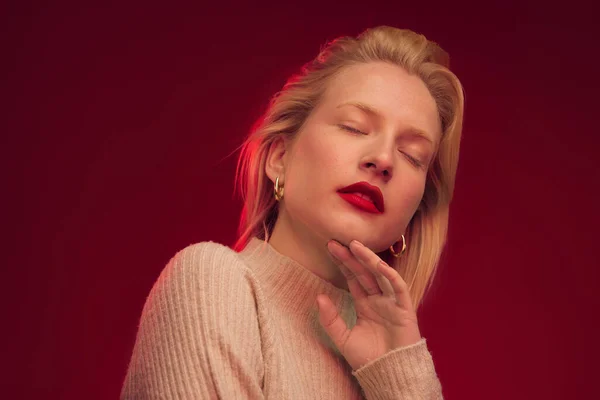 Studio Shot Van Een Ernstige Blonde Vrouw Poseren Rode Achtergrond — Stockfoto