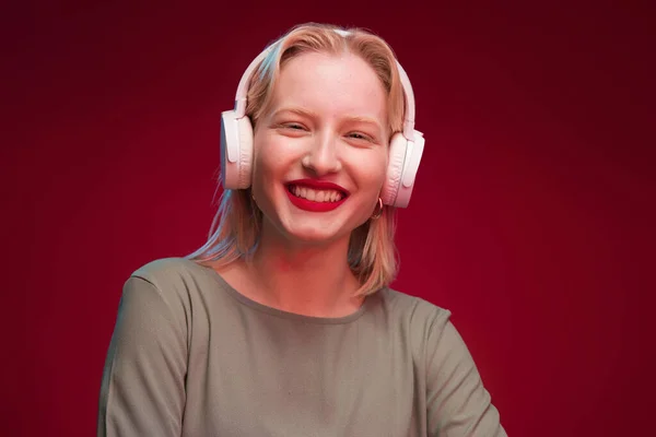 Счастливая Блондинка Наслаждается Музыкой Позируя Студии Красном Фоне — стоковое фото