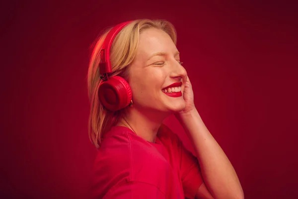 Happy Blonde Enjoying Music While Posing Studio Isolated Red Background — Foto Stock