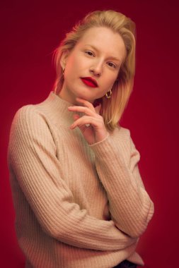 Kırmızı arka planda tek başına duran ciddi bir kadının güzel portresi..