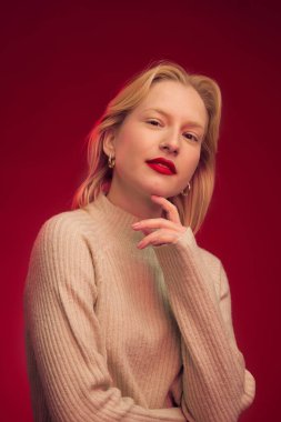 Beauty portrait of a pretty blonde with natural pure skin looking at the camera isolated on red background.