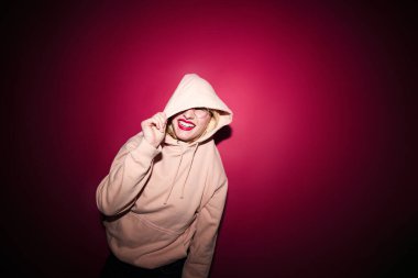 A cheerful young blond woman dancing in studio isolated on magenta background. Viva magenta, color of the year.