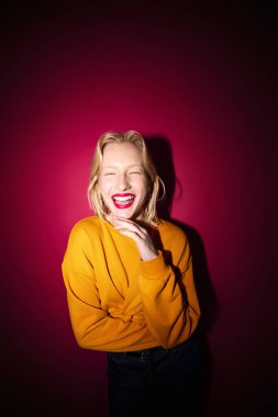 A young beautiful blond woman posing in studio isolated on magenta background. Viva magenta, color of the year.