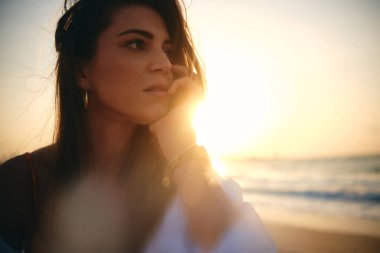 Bir kadının yüzüne sanatsal açıdan yakın çekim, güneş ışığı etkisi ve derin düşüncelere dalma.