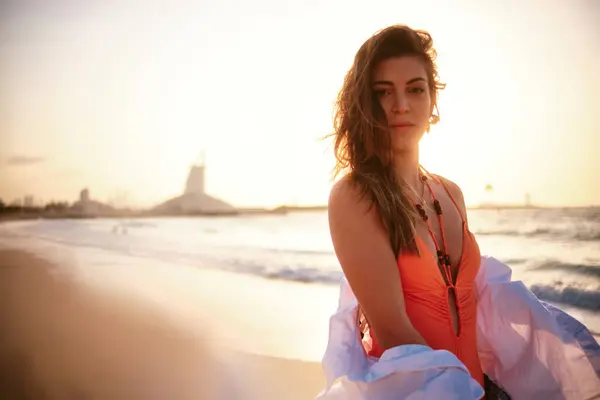 日没のビーチで流れる白い衣服と水着のエレガントな女性 ロイヤリティフリーのストック画像