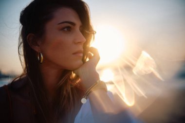 Bir kadın, güneşe yakın çekim çekilirken görüntülenir. Sıcak bir arka plan ışığı yaratır ve siluet etkisi yaratır.