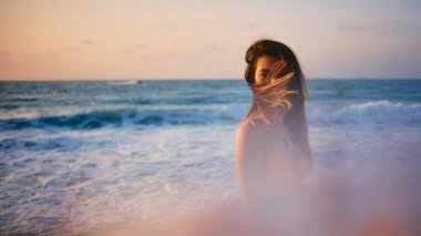 Gün batımında denize bakan rahat kadın yumuşak odak etkisiyle