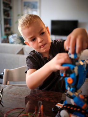 Görevine dalmış genç bir çocuk, bu sonbahar sabahı modern bir evde yoğun bir odak ve konsantrasyon ortamı yaratarak karmaşık bir robot yapıyor..