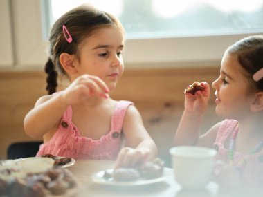Küçük kız güneşli bir öğleden sonra sıcak bir mutfakta ailesiyle kek pişiriyor.
