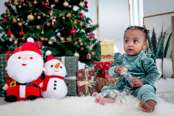 美しいアフリカ系アメリカ人の少女の肖像子供はクリスマスツリーの下で多くのギフトボックスプレゼントとリビングルームの床に白いカーペットの上に座って 子供は幸せなクリスマス冬の休日を祝う — ストック写真