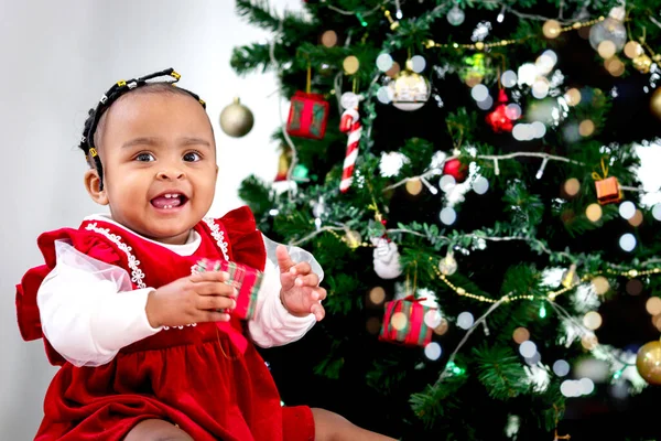愛らしい笑顔の肖像アフリカ系アメリカ人の女の子の子供は リビングルームの床にクリスマスツリーの下に小さなギフトボックスを保持し 子供は幸せなクリスマス冬の休日を祝う — ストック写真