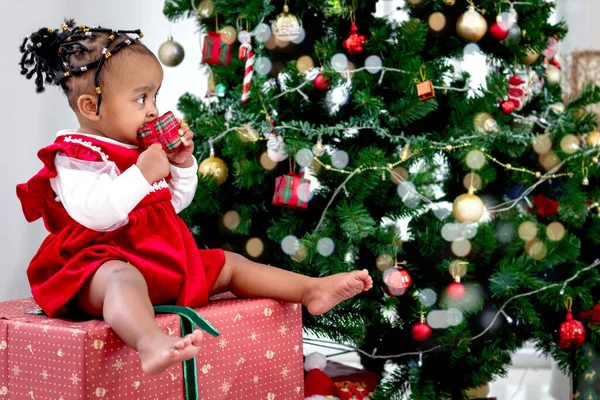 愛らしい笑顔の肖像アフリカ系アメリカ人の女の子の子供は大きなギフトボックスに座っているリビングルームでクリスマスツリーの下に存在し 子供は幸せなクリスマス冬の休日を祝う — ストック写真