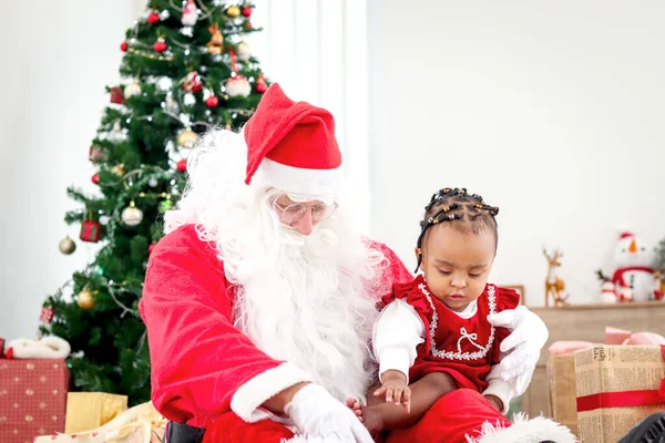 Uroczy Szczęśliwy Uśmiechnięty Afroamerykańskie Dziecko Dziewczyna Siedzi Kolanach Świętego Mikołaja — Zdjęcie stockowe