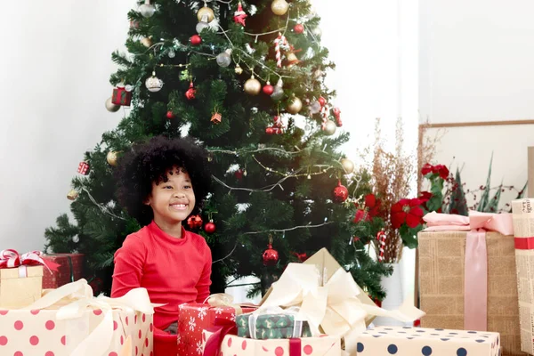 愛らしい笑顔の肖像黒カレーの髪を持つアフリカ系アメリカ人の女の子の子供装飾的なクリスマスツリーの下にクリスマスプレゼントギフトボックスを保持し 子供は幸せなクリスマス冬の休日を祝う — ストック写真