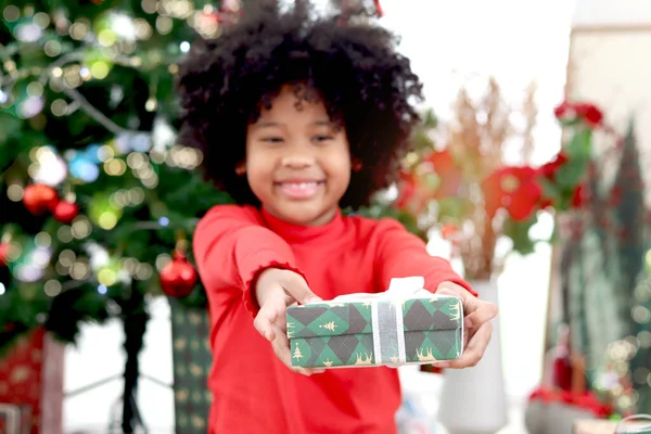 クリスマスプレゼントギフトボックスの手に愛らしい笑顔アフリカ系アメリカ人の女の子の子供と黒カレーの髪装飾的なクリスマスツリーの下で開催され 子供は幸せなクリスマス冬の休日を祝う — ストック写真
