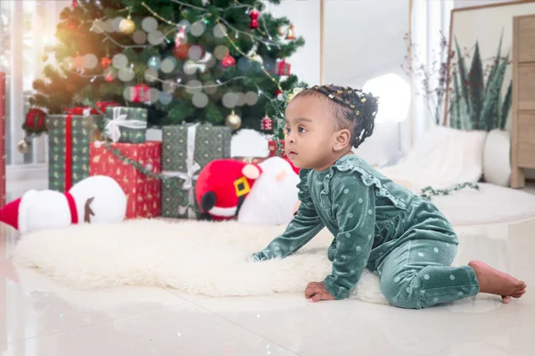 美しいアフリカ系アメリカ人の女の子の子供の肖像クリスマスツリーの下で多くのギフトボックスプレゼントとリビングルームの床に白いカーペットの上に登る 子供は幸せなクリスマス冬の休日を祝う — ストック写真