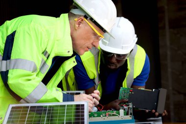 Elektronik devre kartı ve güneş pilleriyle çalışan iki elektrik mühendisi, mekanikler üst düzey beyaz ve Afrikalı Amerikalı erkekler birlikte çalışıyor, Mutlu çeşitlilik uyumu insanları.