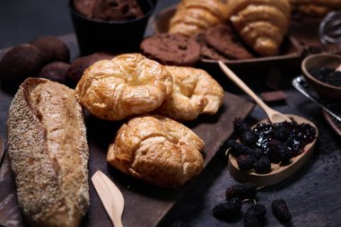 Tatlı hamur işleri, taze tereyağlı kahvaltı kruvasanları ekşi hamur işleri, poğaça, ekmek ve ahşap masada bir sürü tatlı, nefis ev yapımı fırın konseptleri.