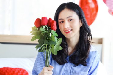 Attractive and beautiful Asian woman holding red rose bouquet , portrait of happy smiling girl holding Valentine flower present from lover boyfriend. Happy Saint Valentine Day.
