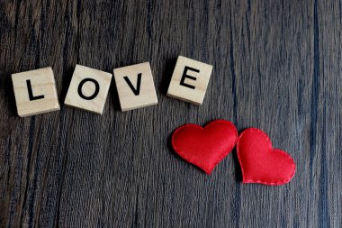 Kaba kahverengi tahta yüzeyde aşk ve kırmızı kalp kelimelerini heceleyen tahta bloklar, Sevgililer Günü 'nü kutlamak için romantik bir arka plan, birbirine aşık çiftler birliği..