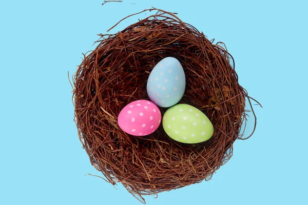 青い背景 装飾やお祝いの鳥の巣の中の美しいカラフルなイースターの卵のトップビューイースターと春の始まり — ストック写真