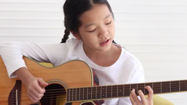 Cute Happy Asian Girl Long Hair Braided Pigtails Playing Acoustic — Stockvideo