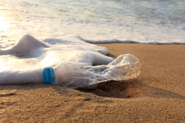 Beyaz köpüklü plastik şişe atığı tropikal kum plajına okyanus dalgası, sahile çöp ve deniz kirliliği konsepti..