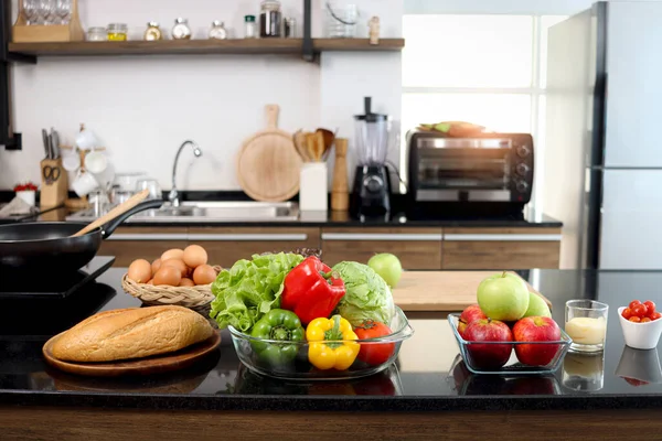 玻璃杯中色彩艳丽的新鲜蔬菜沙拉和餐桌柜台厨房上的食品配料 背景模糊 有漂亮的现代厨房 健康的自然食品概念 有复制空间 — 图库照片