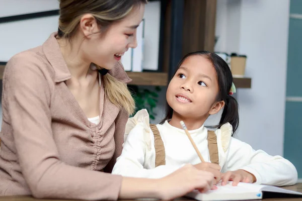亚洲可爱的小女孩在家里和妈妈一起学习功课 女学生和家庭教师一起做作业 快乐的孩子在笔记本上写作 家庭教育 — 图库照片