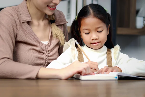 亚洲可爱的小女孩在家里和妈妈一起学习功课 女学生和家庭教师一起做作业 快乐的孩子在笔记本上写作 家庭教育 — 图库照片