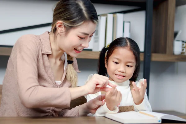 亚洲女孩在家里和母亲一起学习数学课 女学生和家庭教师一起做数学作业 认为孩子们是通过数手指来学习计算的 而家里的孩子是通过教育来学习计算的 — 图库照片