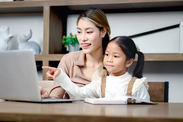 亚洲女孩在家里用笔记本电脑和妈妈上网 指的是电脑 女生在网上远程学习 在家里和家教老师一起做作业 学生在学习 孩子在教育 — 图库照片